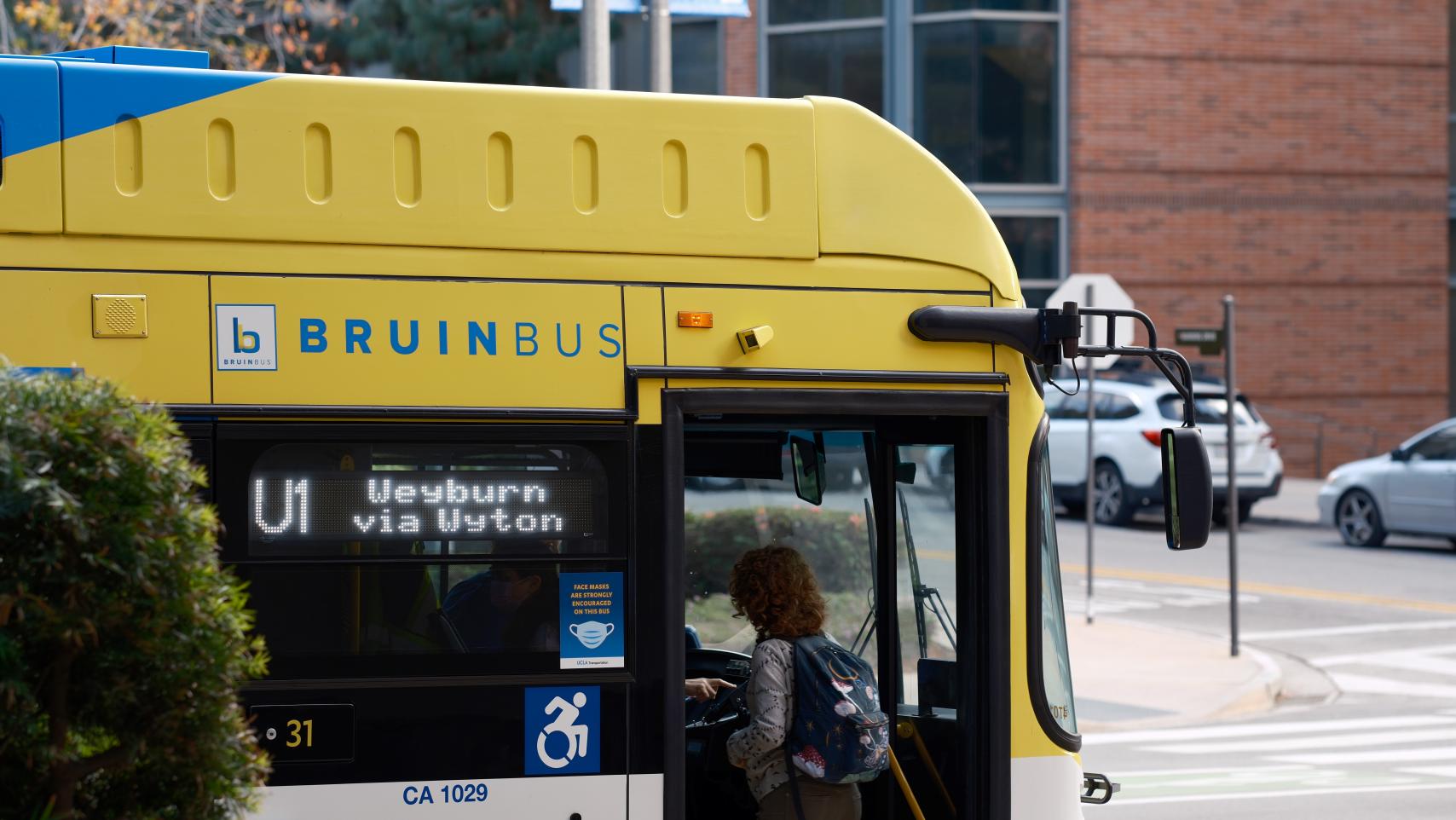 A student walks onto the Bruin Bus.
